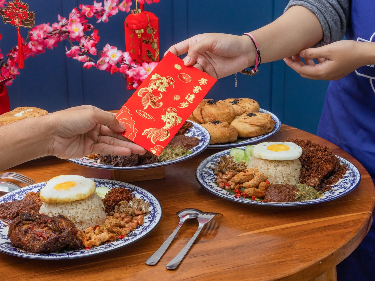 A red envelope passed across a table of nasi lemak during Chinese New Year